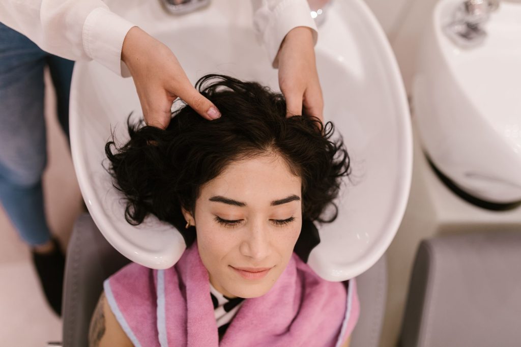 Praticienne effectuant un soin du cuir chevelu sur une table de head spa professionnel en institut haut de gamme
