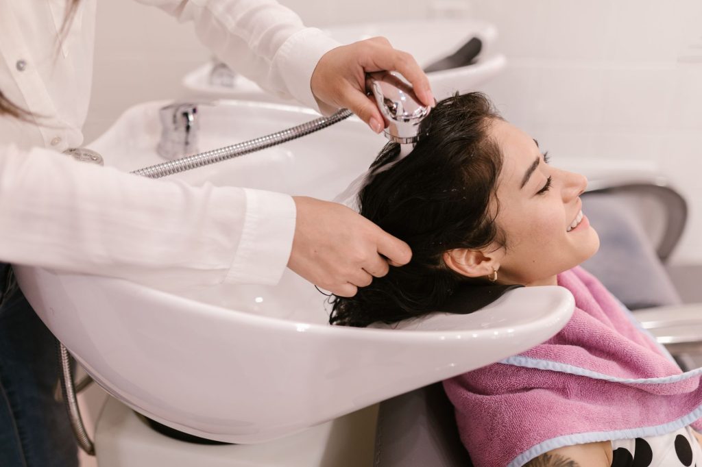 Cliente recevant un soin head spa professionnel dans un institut haut de gamme avec matériel spécialisé.