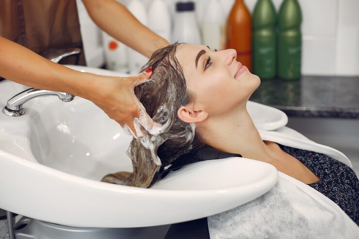 Une coiffeuse lave les cheveux d'une cliente dans un salon de coiffure professionnel